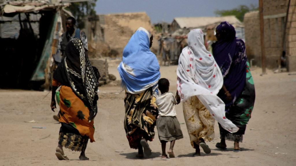 Aikuisia ja lapsi takaa päin kuvattuna kävelemässä ulkona Somalimaassa.